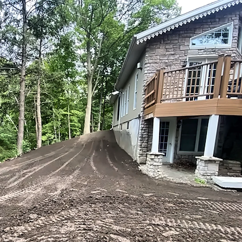 Terrain nivelé et compacté devant une maison en pierre